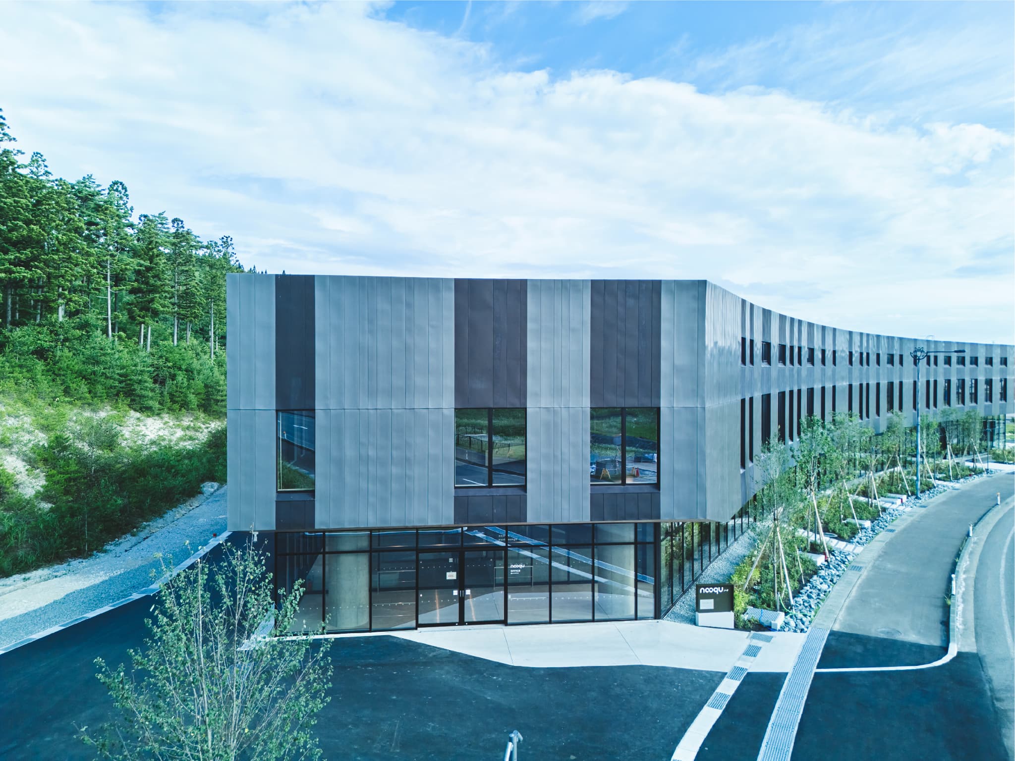 青い外壁のnooqu建物、エントランスと周辺の自然環境