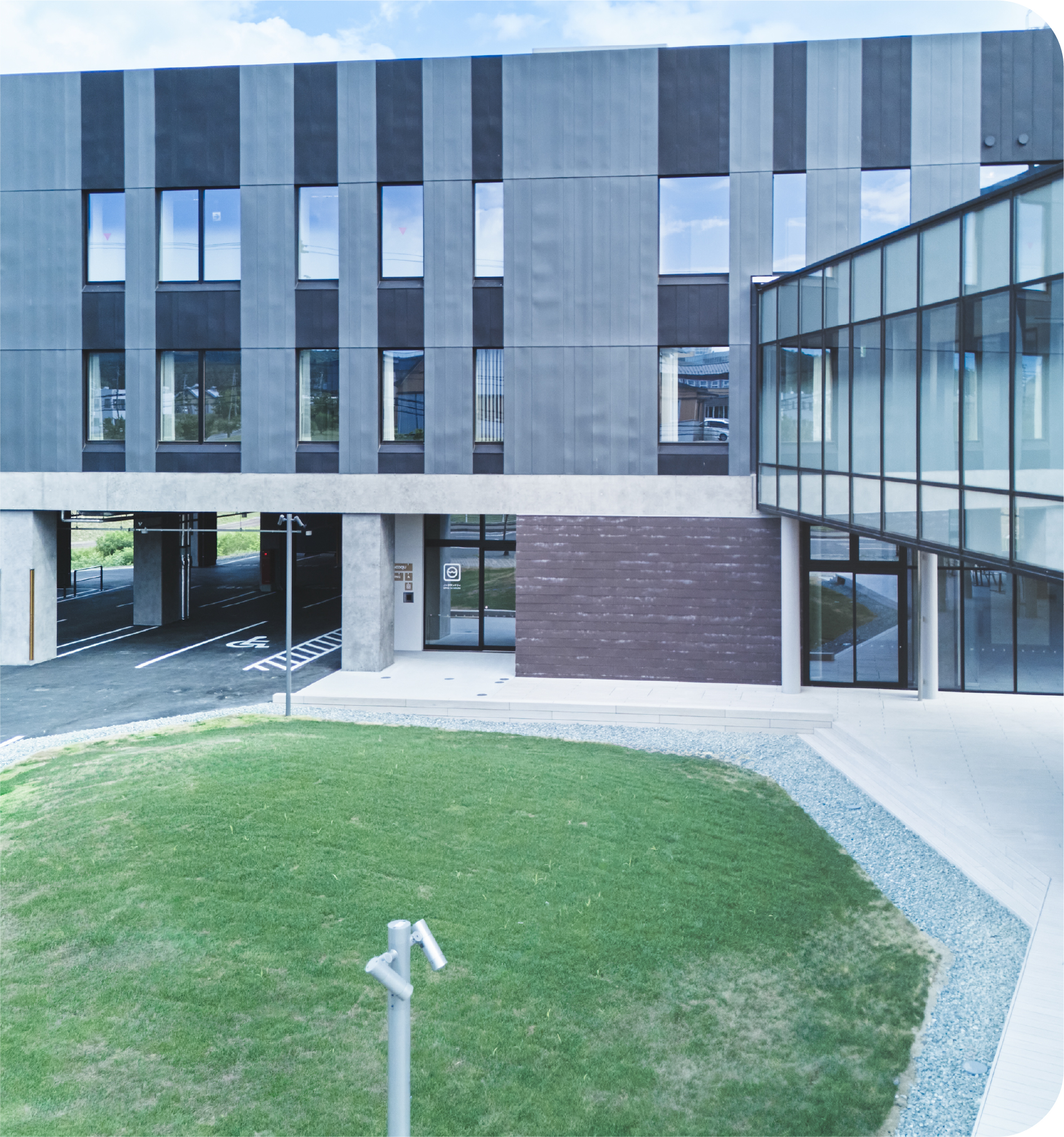 nooqu施設の屋外ガーデン、芝生エリアと青いモダンな建物