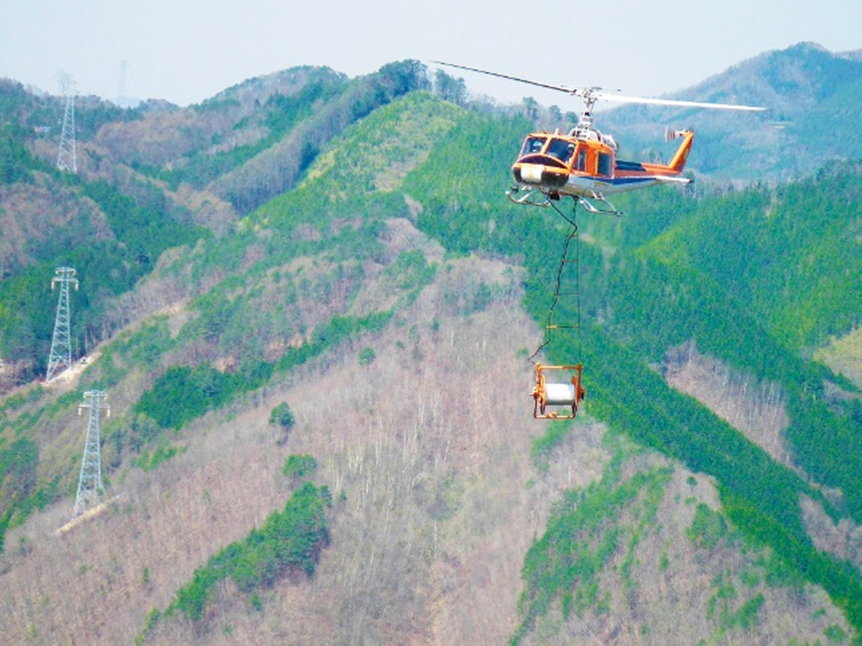山岳部では人力で鉄塔間に電線を張ることは難しいためヘリコプターで行う